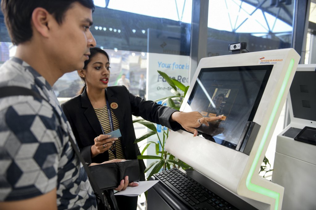 An airport staff member shows a passenger how to register his personal details at a facial recognition counter. Source: AFP