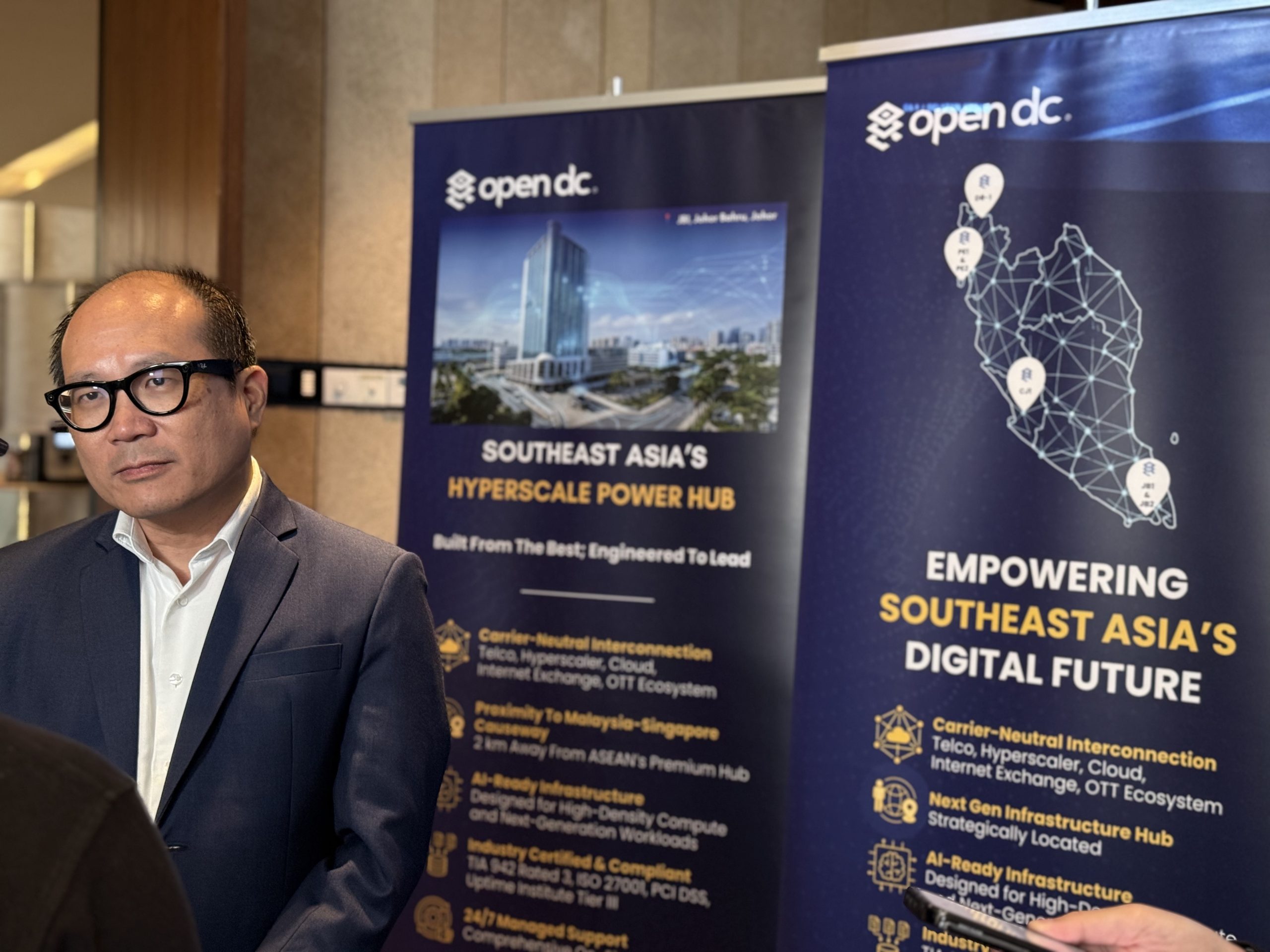 Open DC managing director Wong Weng Yew speaking at a media briefing beside a Malaysia internet exchange and data centre network map